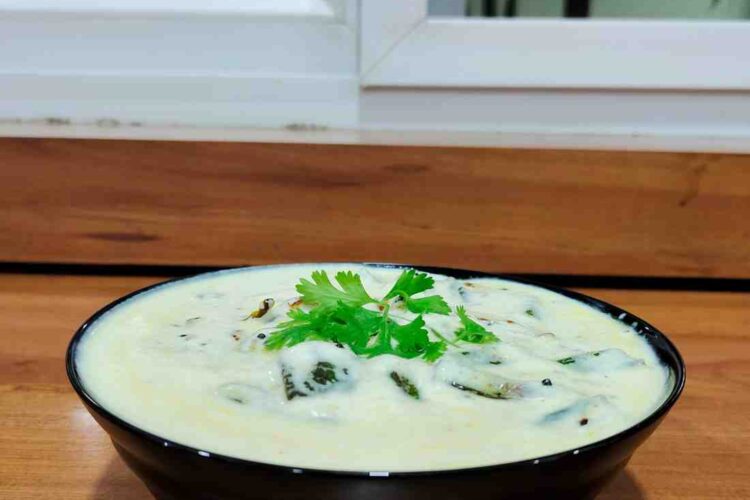A bowl of Dahi Bhindi, a North Indian dish, showcasing tender okra in a tangy yogurt-based gravy, garnished with fresh coriander leaves, served warm or cold with roti, paratha, or rice. The dish is ready in 30 minutes, making it a perfect choice for a quick and satisfying weeknight dinner.