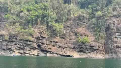 Layered rock cliffs above the green Umngot river